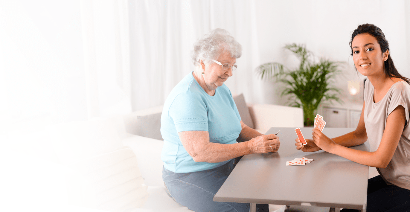 Hospice life volunteer playing cards with elderly lady