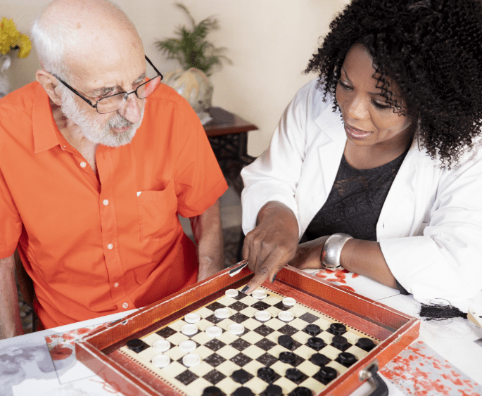 Hospice life volunteer playing chess with elderly patient